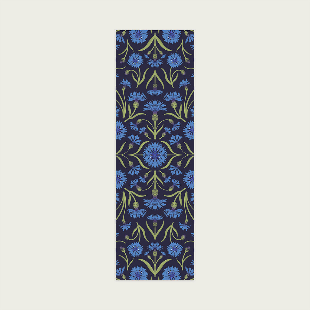 The Heritage Cornflower Bookmark features a symmetrical floral pattern with blue flowers and green leaves on a dark background, inspired by 19th-century pattern design.