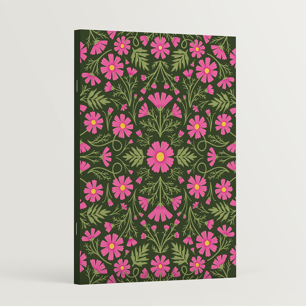 The Heritage Cosmos Notebook is an A5 eco-friendly notebook with a symmetrical floral design of pink flowers and green leaves on a dark cover, crafted from recycled paper for sustainable note-taking.