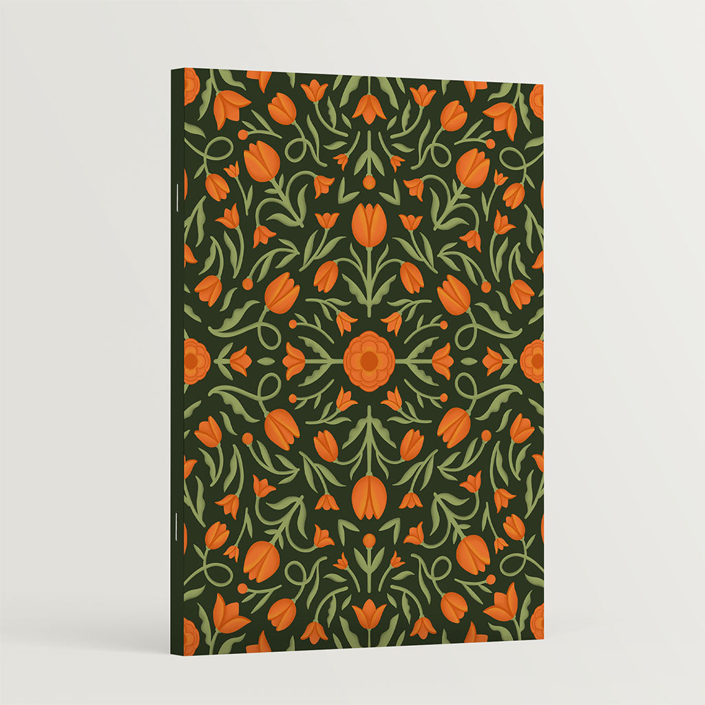 The Heritage Tulips Notebook, with its vintage-inspired cover of orange and green tulips on a dark background, is displayed standing against a plain white surface.