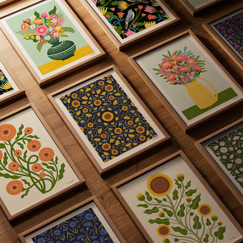 A collection of framed floral illustrations in various styles and colors is arranged on a wooden wall.