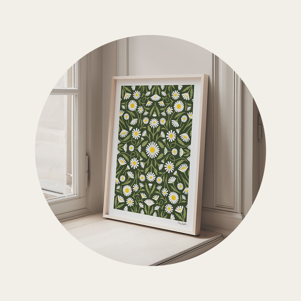 An art print with a daisy design sitting propped against wood panelling in a deep window recess.