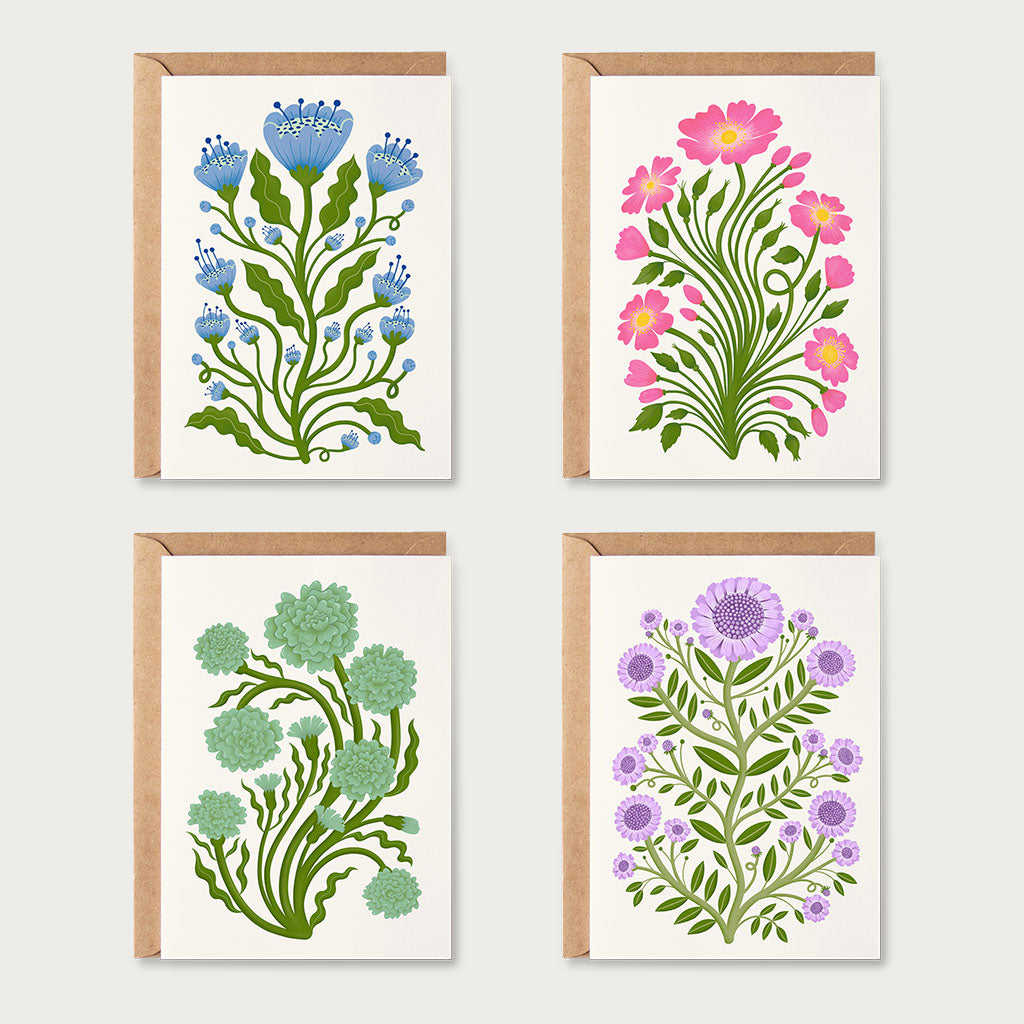 The Folk Flowers Greetings Card Set includes four unique botanical art cards: blue, pink, green, and purple flowers are illustrated in a vintage floral art style, with brown kraft paper envelopes.