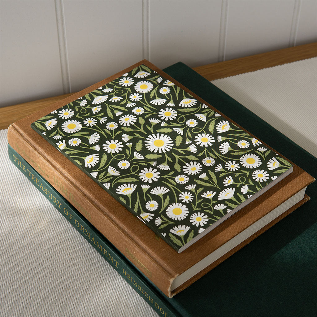 The Heritage Daisies Notebook features a vintage-inspired rectangular cover with white daisies, and green leaves on a dark green background—ideal for floral-themed journaling or creative notes.