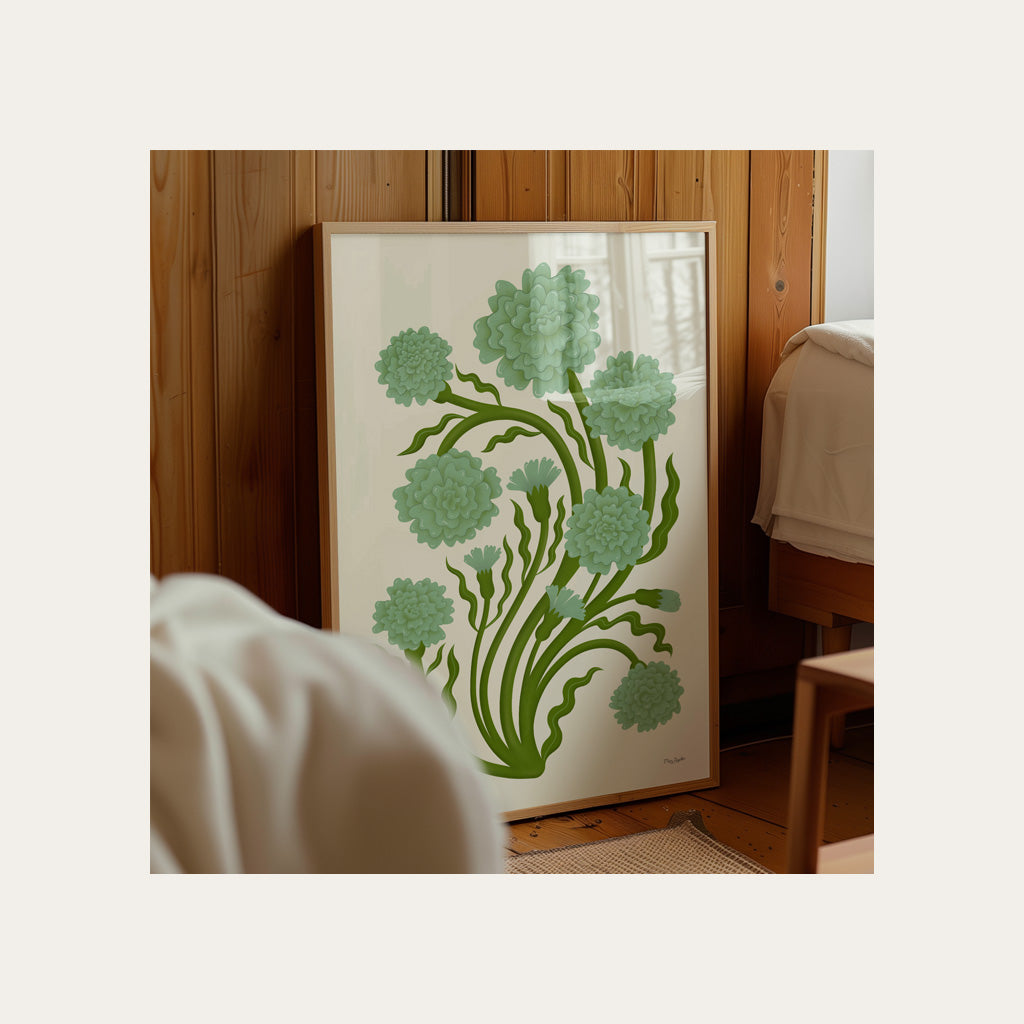 A framed botanical print with green flowers and leaves rests against a wooden wall beside a bed in a softly lit room.