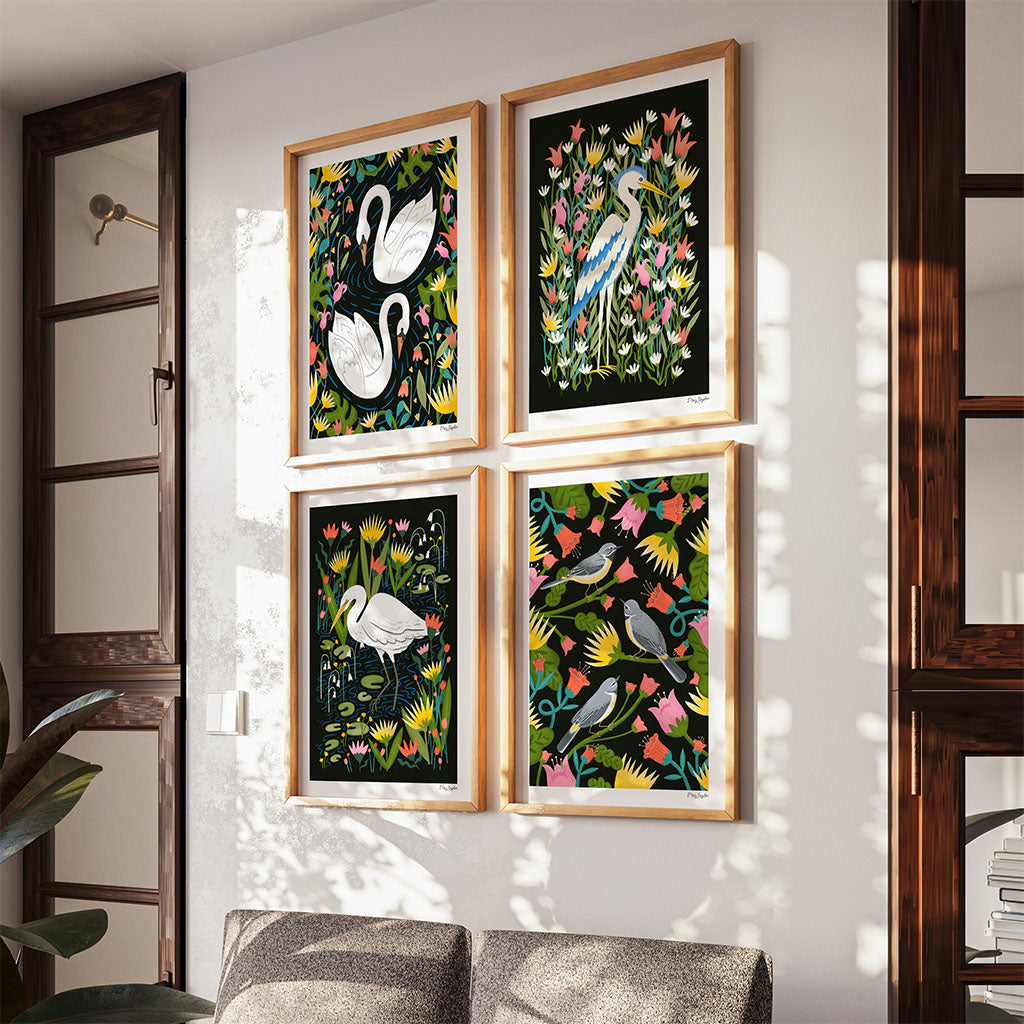 The British Birds Art Print Set featuring four illustrated prints: a graceful swan, a heron, a great egret, and grey wagtails nestled among colourful flowers and foliage.