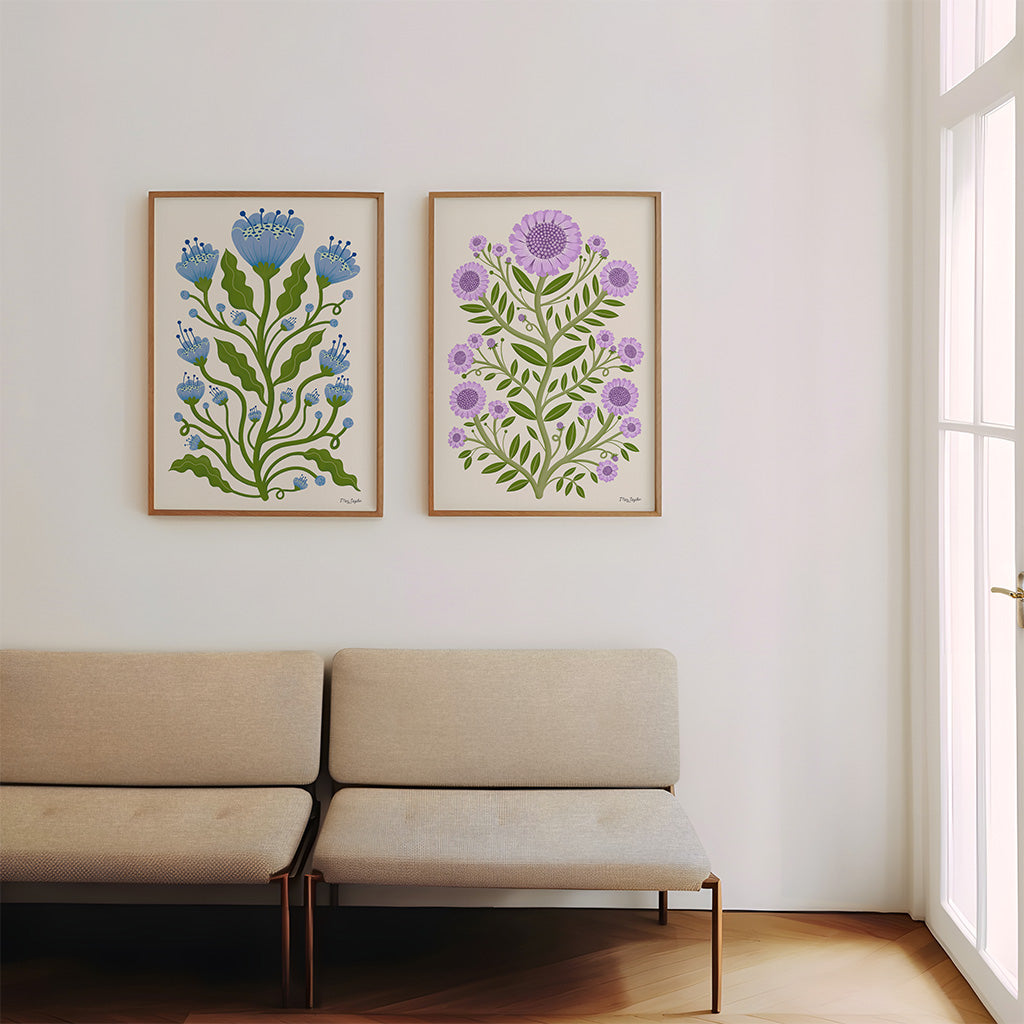 The Folk Flower set of two botanical prints, one with blue poppies and green stems, the other with purple blooms, both on ivory backgrounds, showcasing timeless floral charm.