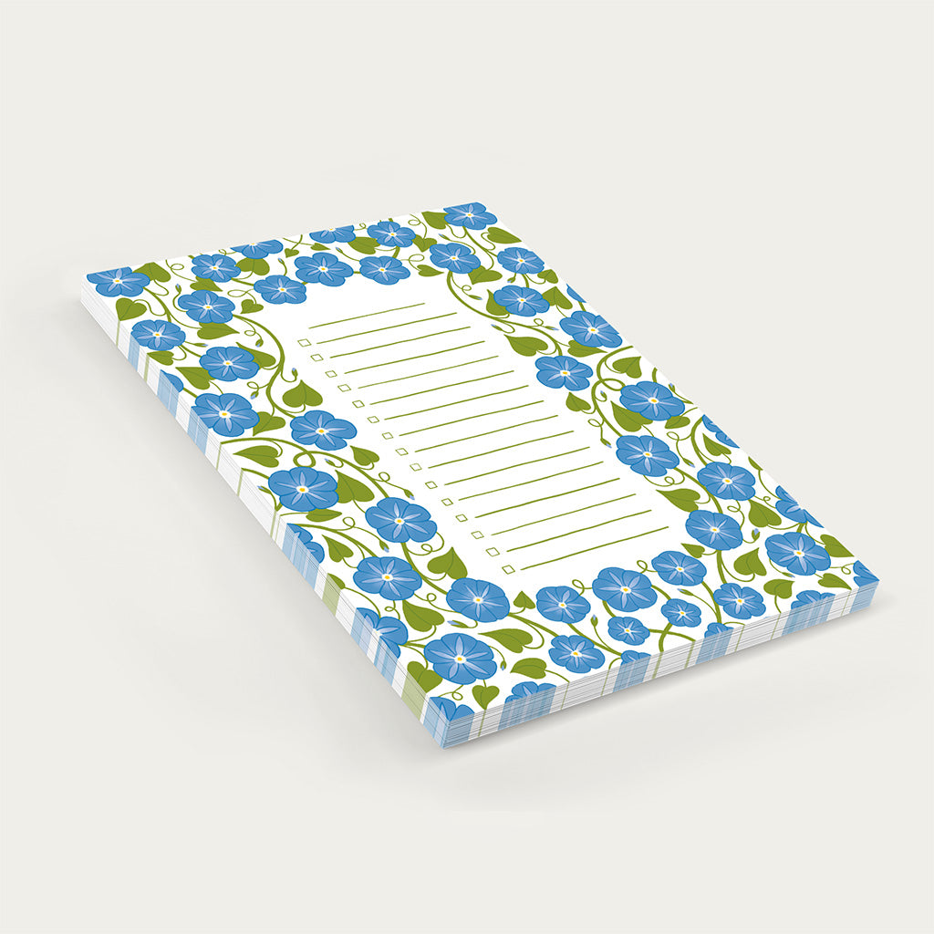 The Heavenly Blue Floral Notepad features a rectangular design with a blue and green floral border and lined centre, ideal for shopping lists or organising daily tasks, displayed on a plain white background.