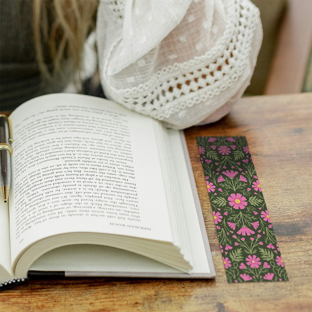Heritage Cosmos Bookmarks are rectangular bookmarks with a symmetrical floral pattern of pink flowers and green leaves on a dark background, crafted from sustainable materials.
