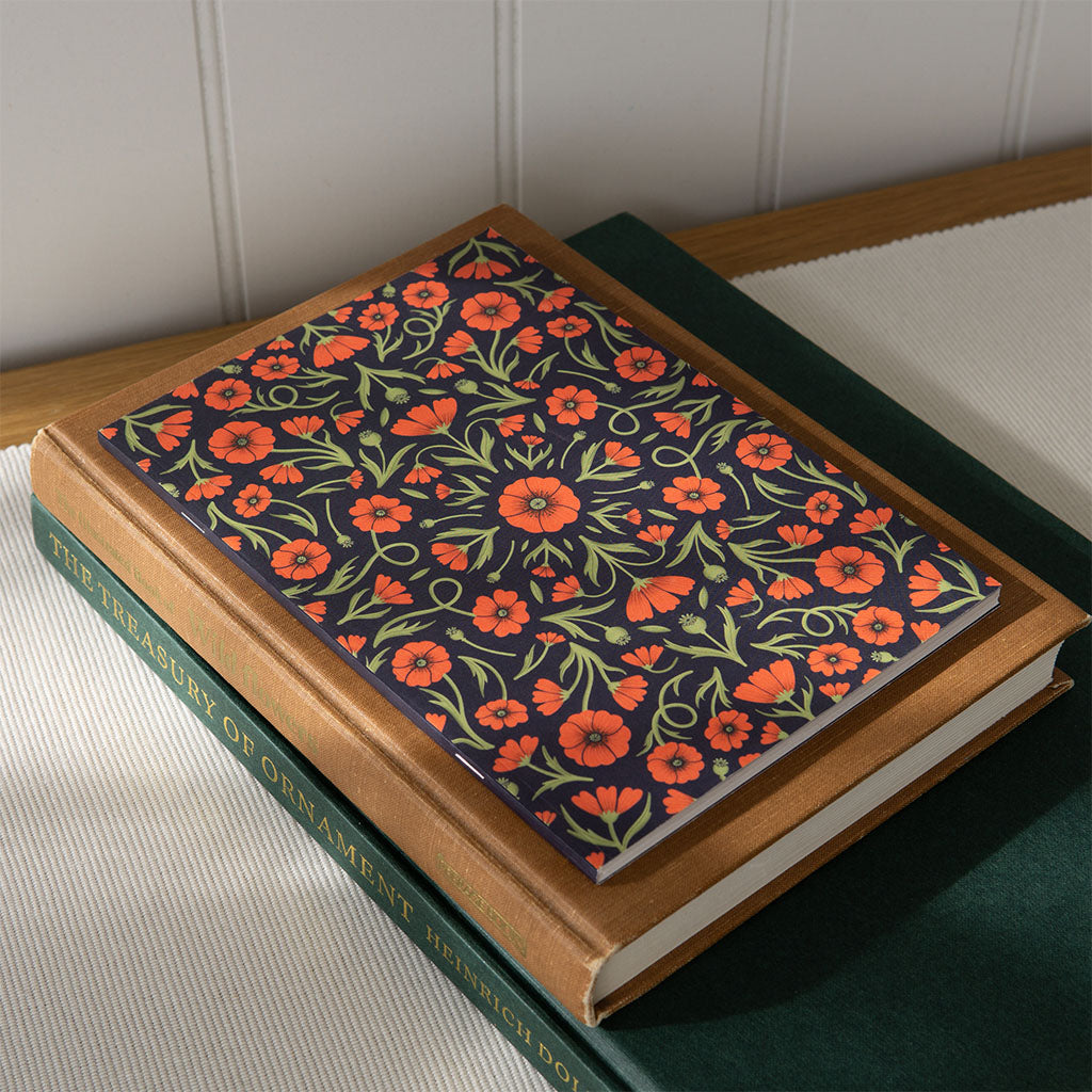 The Heritage Poppies Notebook features a vintage-inspired dark cover with symmetrical red poppies and green leaves, perfect for journaling.