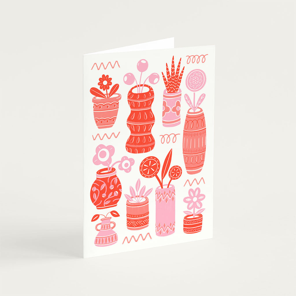 The Red Pots & Plants Greetings Card features abstract red and pink vases with flowers on a light background, an ideal choice for plant lovers.