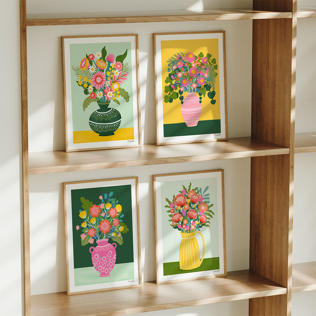 The Flower Vases set of 4 art prints features vibrant illustrated vases with blooming flowers, displayed on wooden shelves as sunlight casts delicate shadows across the colourful scene.