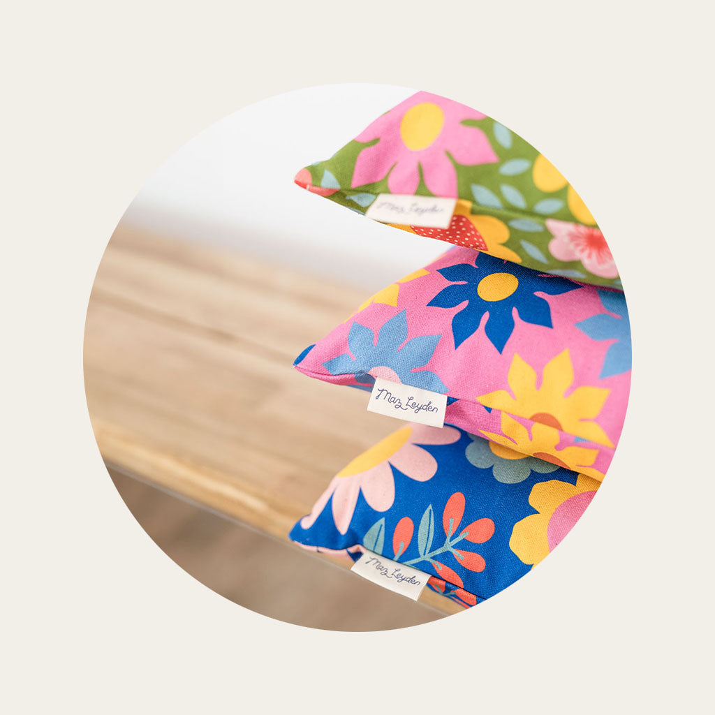 A close up of the edge of a stack of cushions, showing bright retro style fabric design with Maz Leyden labels.