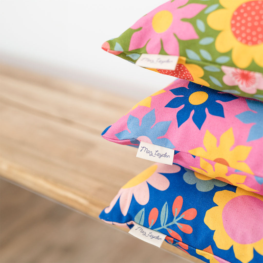 This retro style Cushion features blue and yellow flowers on a pink background. Its vintage floral pattern repeats, bringing retro charm and vibrant style to any space.