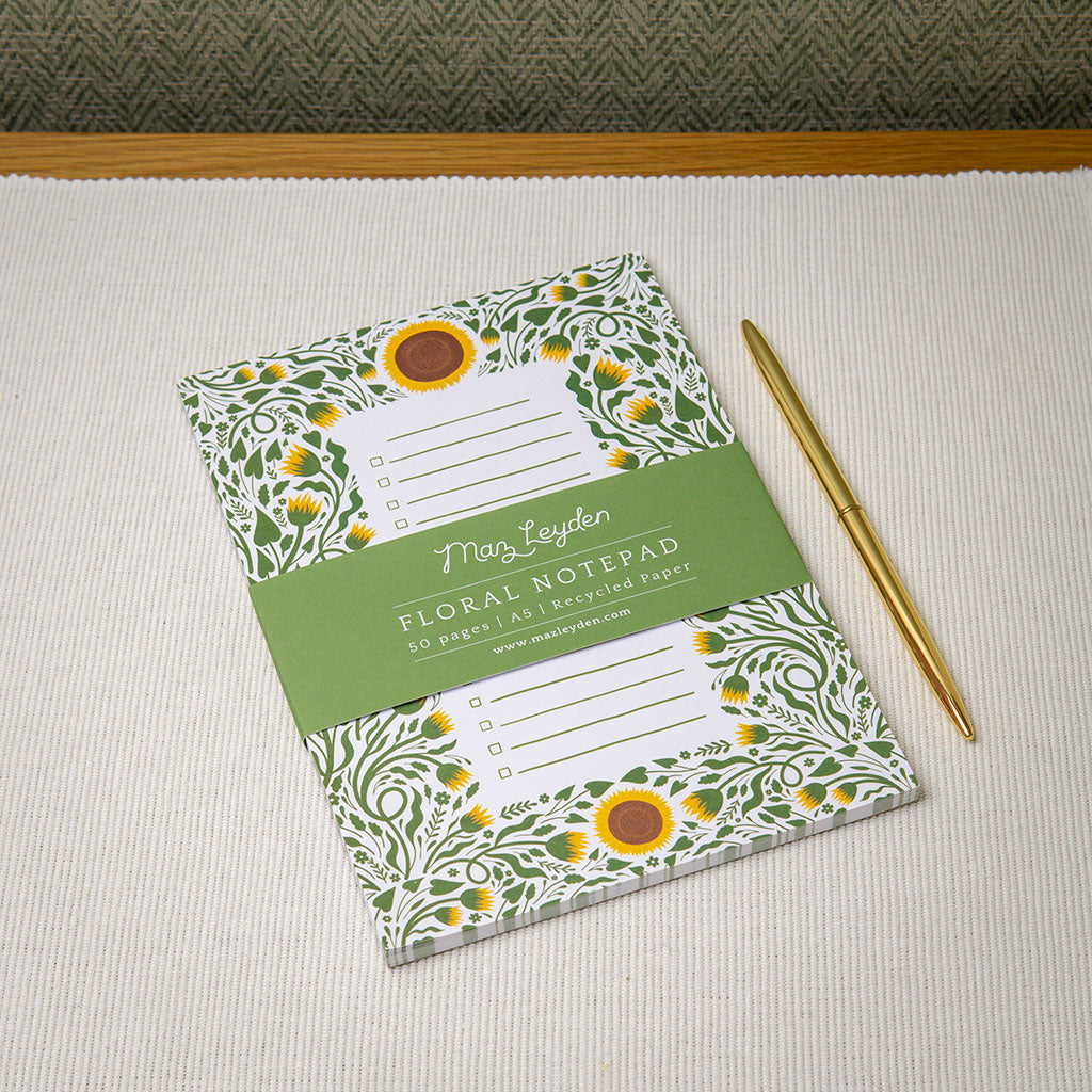 A sunflower design checklist notepad on a desk with stationery.