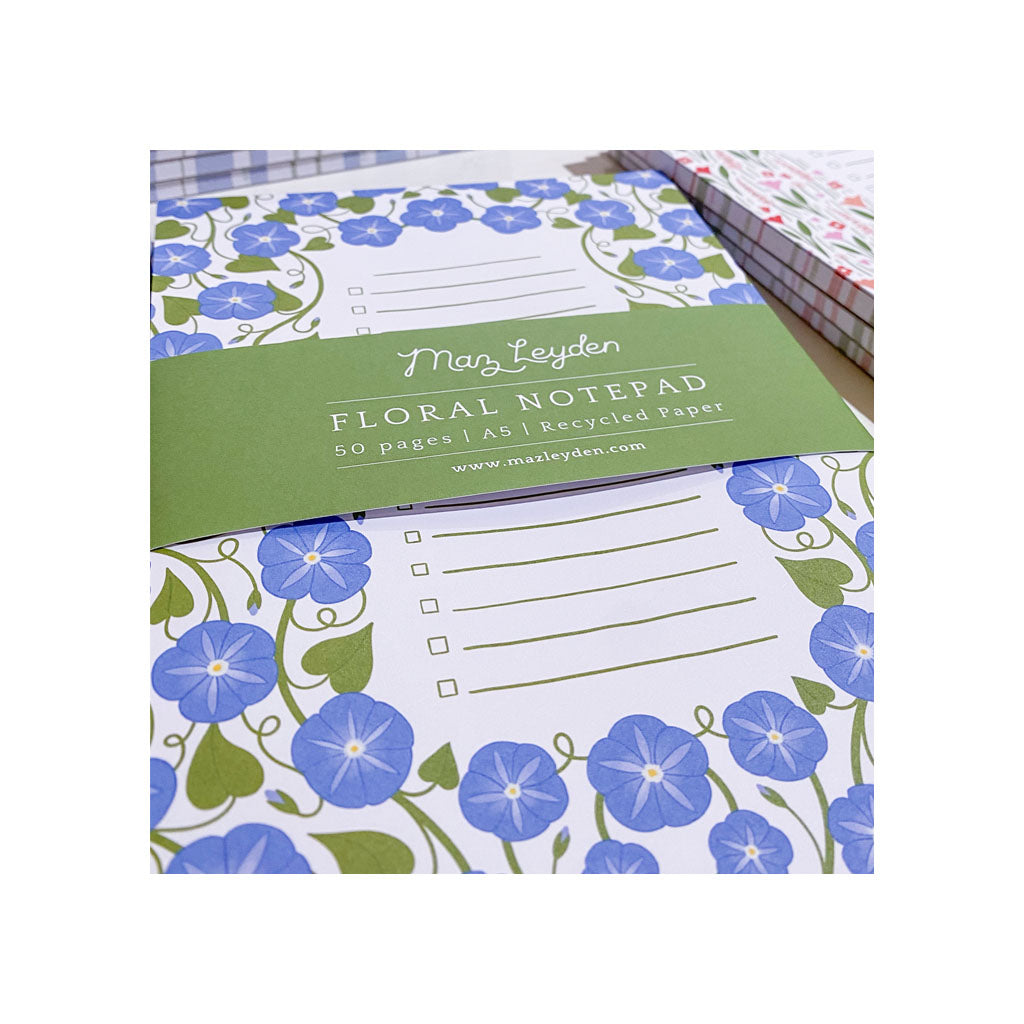 A floral notepad with blue and green flower designs, labeled Maz Leyden Floral Notepad, 50 pages, A5, recycled paper.