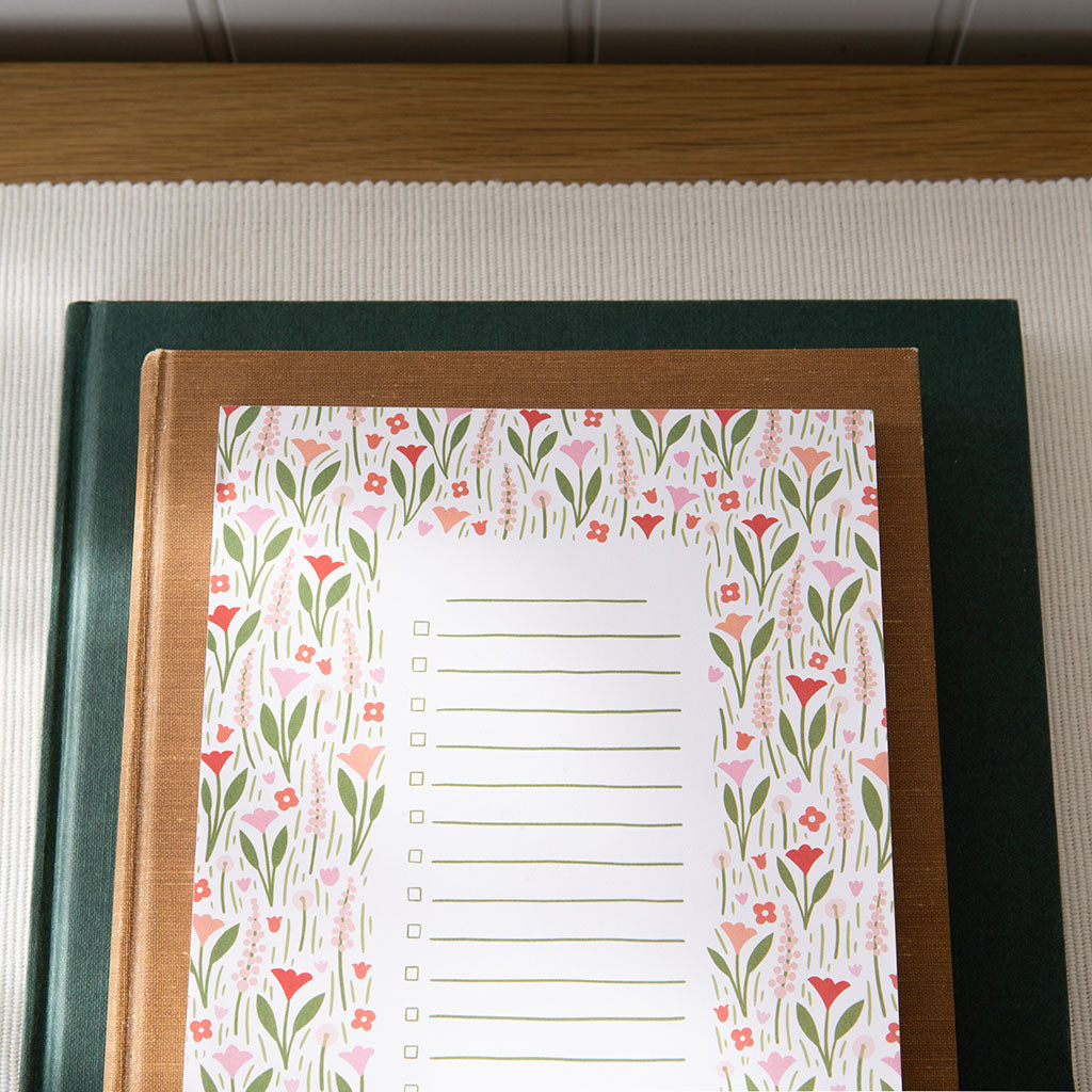 The Blushing Blooms Floral Notepad is a rectangular checklist pad with a floral cover, featuring checkboxes and lines—ideal for shopping lists or daily tasks.