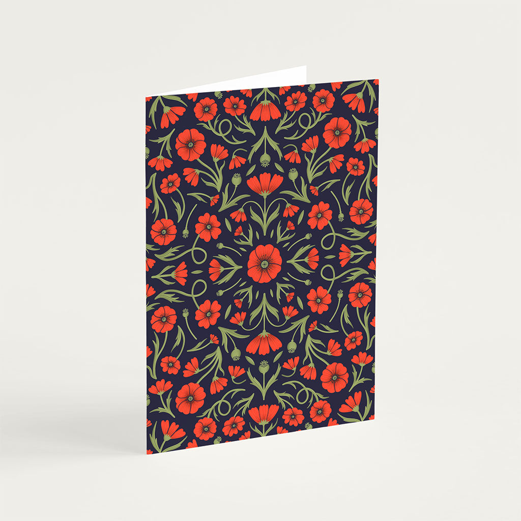The Heritage Poppy Greetings Card stands upright, showcasing red and orange poppies with green leaves on a dark background, printed using vegetable-based inks on sustainably sourced card stock.