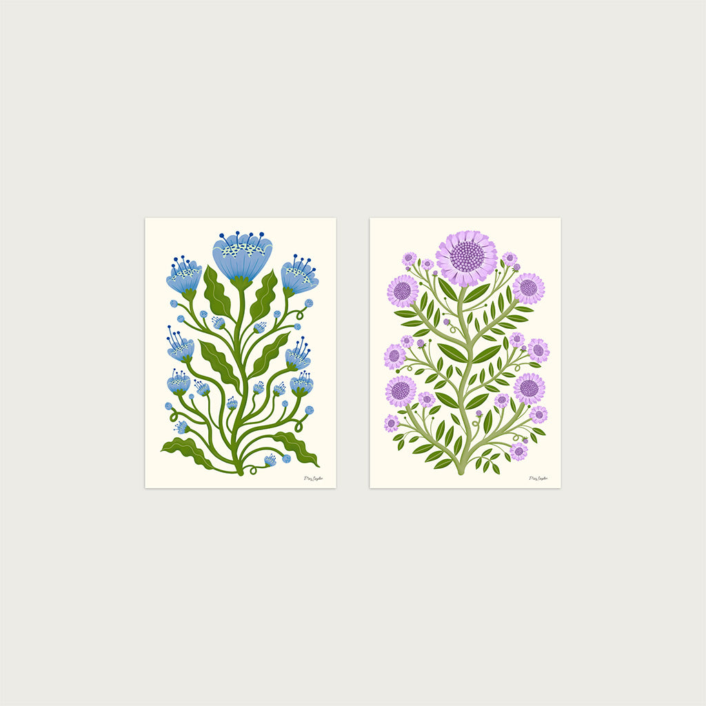 The Folk Flower set of two botanical prints, one with blue poppies and green stems, the other with purple blooms, both on ivory backgrounds, showcasing timeless floral charm.