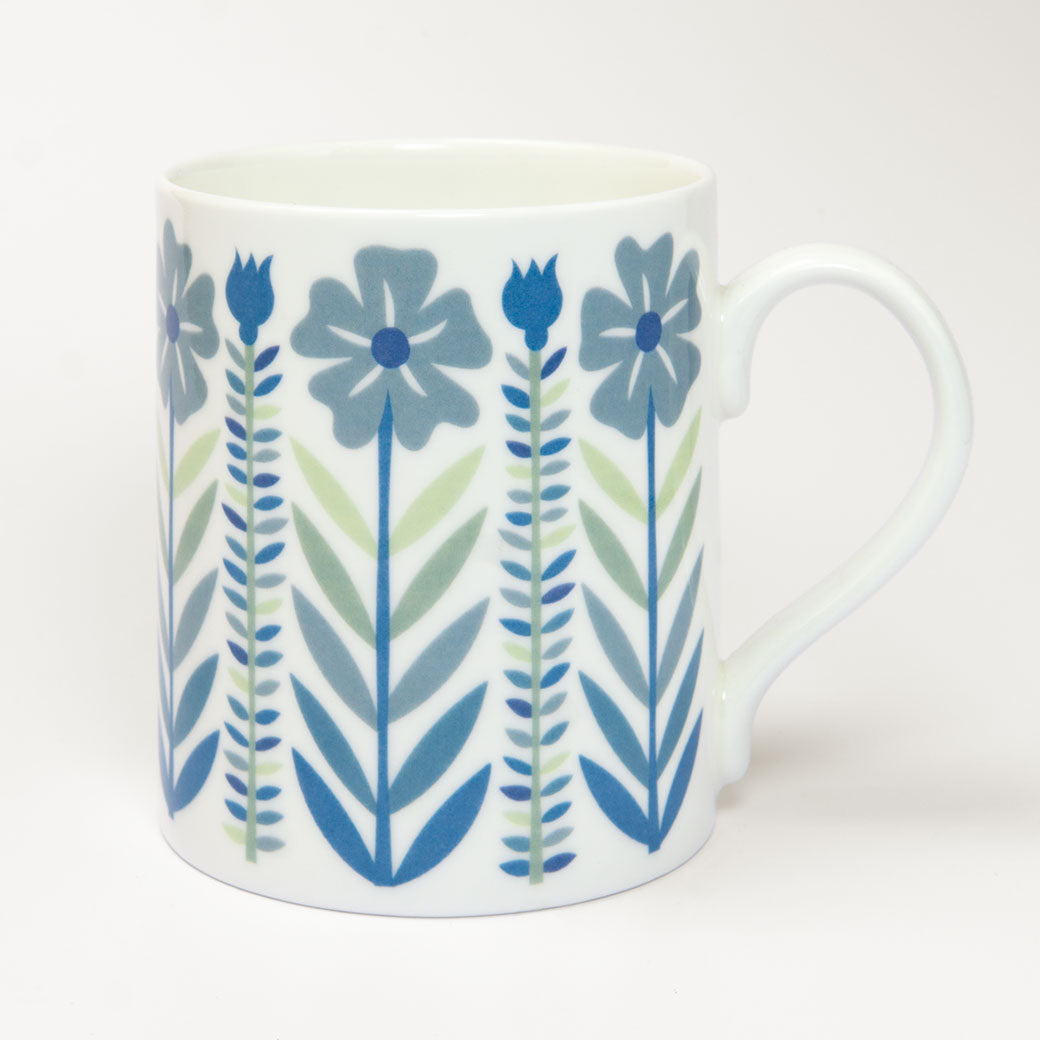 The Vintage Blue Mug is a fine bone china mug, decorated with a mid-century style pattern of illustrated blue and green flowers, stems, and leaves.