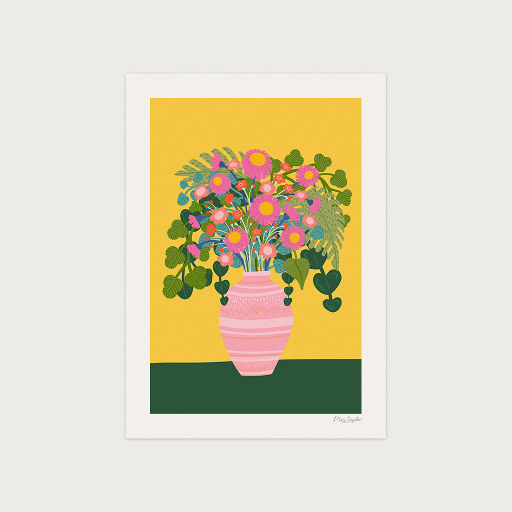 A Flower Vase Art Print features a luxury pink vase filled with pink blooms and green leaves, set on a green surface against a mustard yellow background.