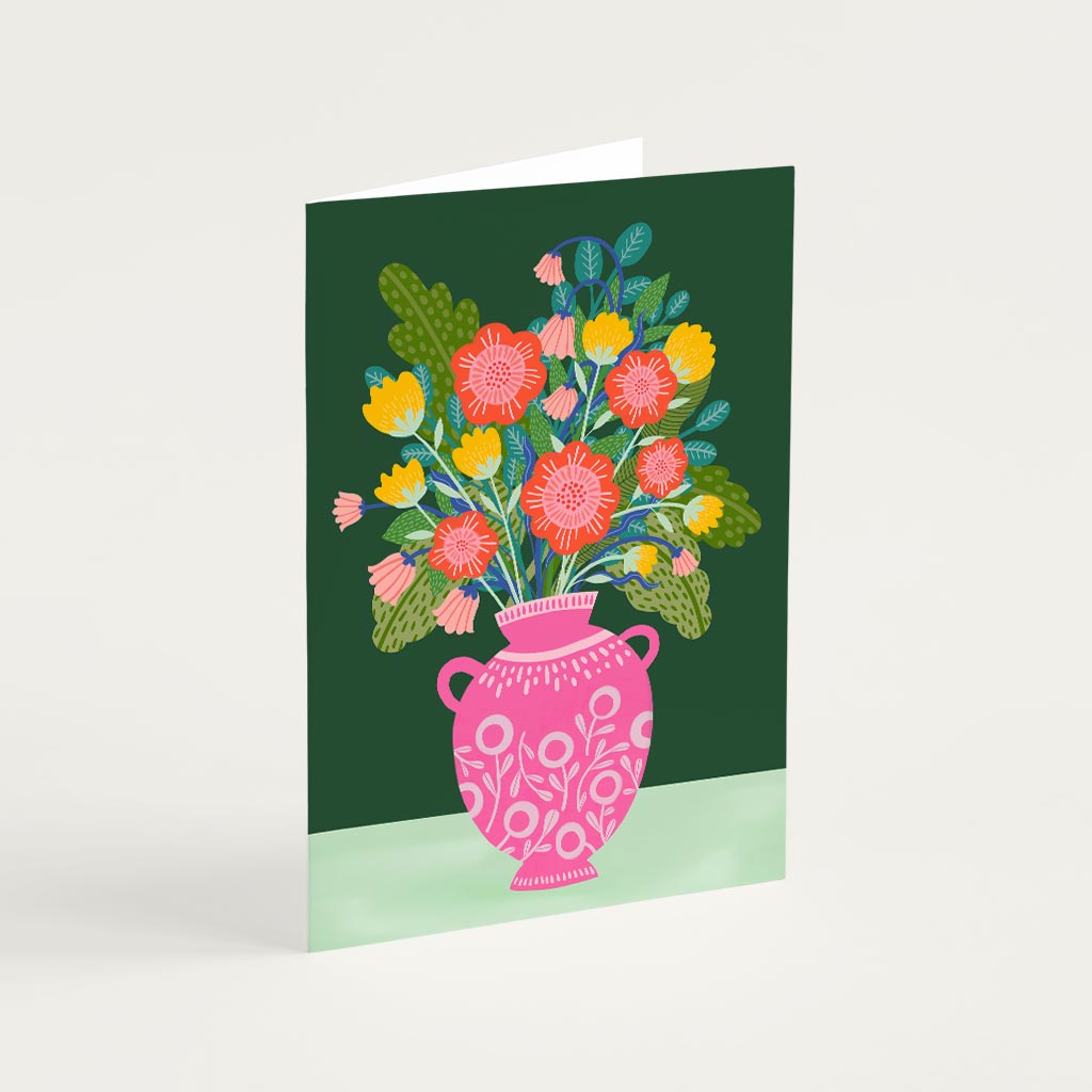 The Flowers in a Vase Greetings Card features an illustrated pink vase of flowers with colourful leaves on a dark green background—perfect for sending a special message.