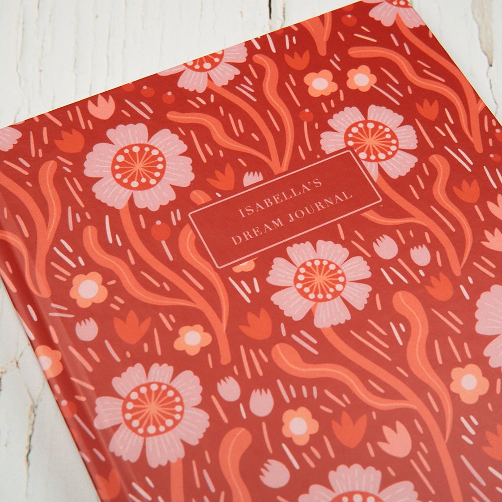 The Red Wildflowers Personalised Notebook is a hardcover with delicate red and pink British wildflower illustrations and a customisable label on the journal's front cover.