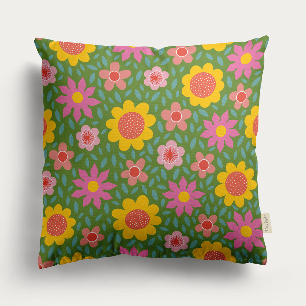 The Lawn Daisies Cushion Cover features a retro, colorful floral pattern on a green background. Made from organic cotton, this square cover adds charm and comfort to any space—perfect for floral cushion lovers.