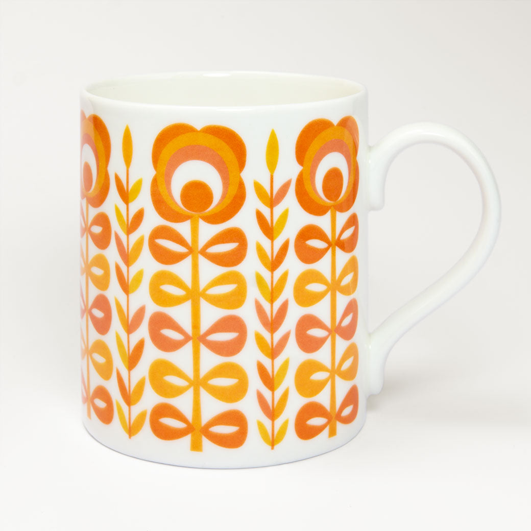 The Vintage Orange Mug is a retro-style white ceramic mug made in the UK, featuring an orange and yellow floral pattern on a plain white background.
