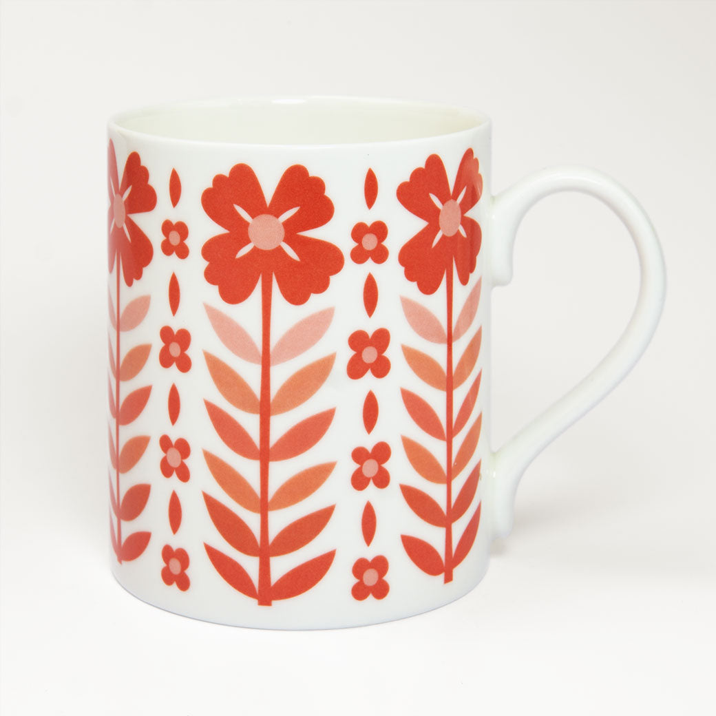 The Vintage Red Mug is a white fine bone china mug with a vintage style and a pattern of red flowers and leaves arranged in vertical rows.