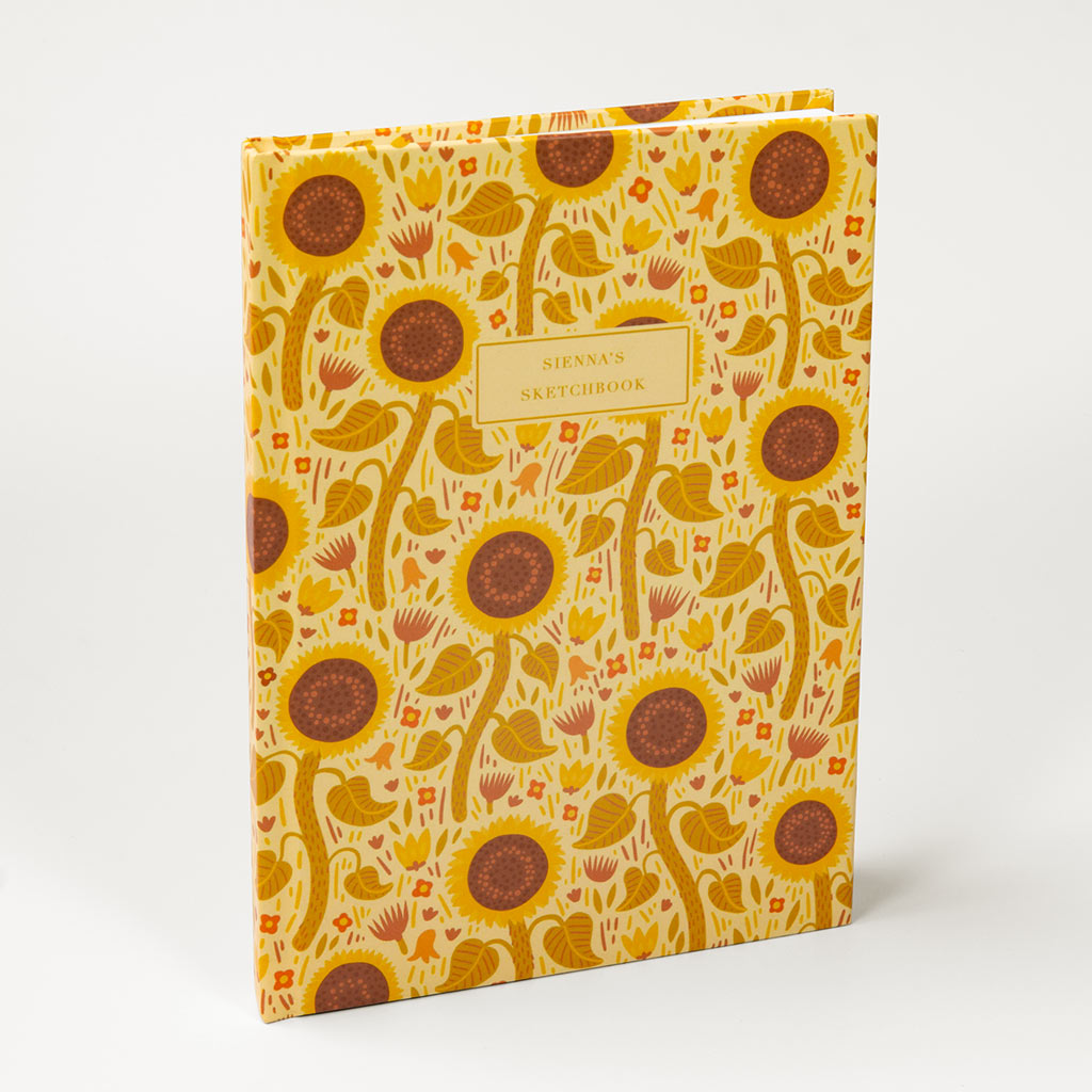 The Yellow Wildflowers Personalised Notebook features a yellow cover with British wildflowers, including sunflowers and foliage, plus a central box for your custom text.